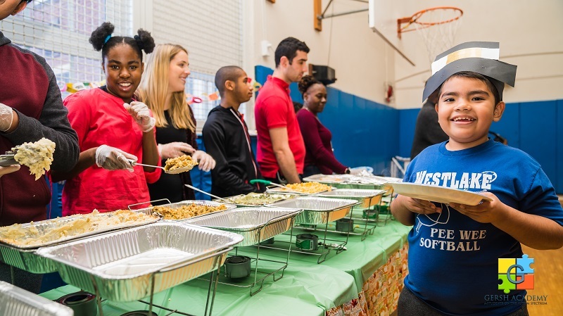 Student Smiling as He Gets Food From a Feast